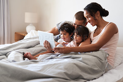 Buy stock photo Shot of a beautiful young family of four using a digital tablet in their bedroom at home