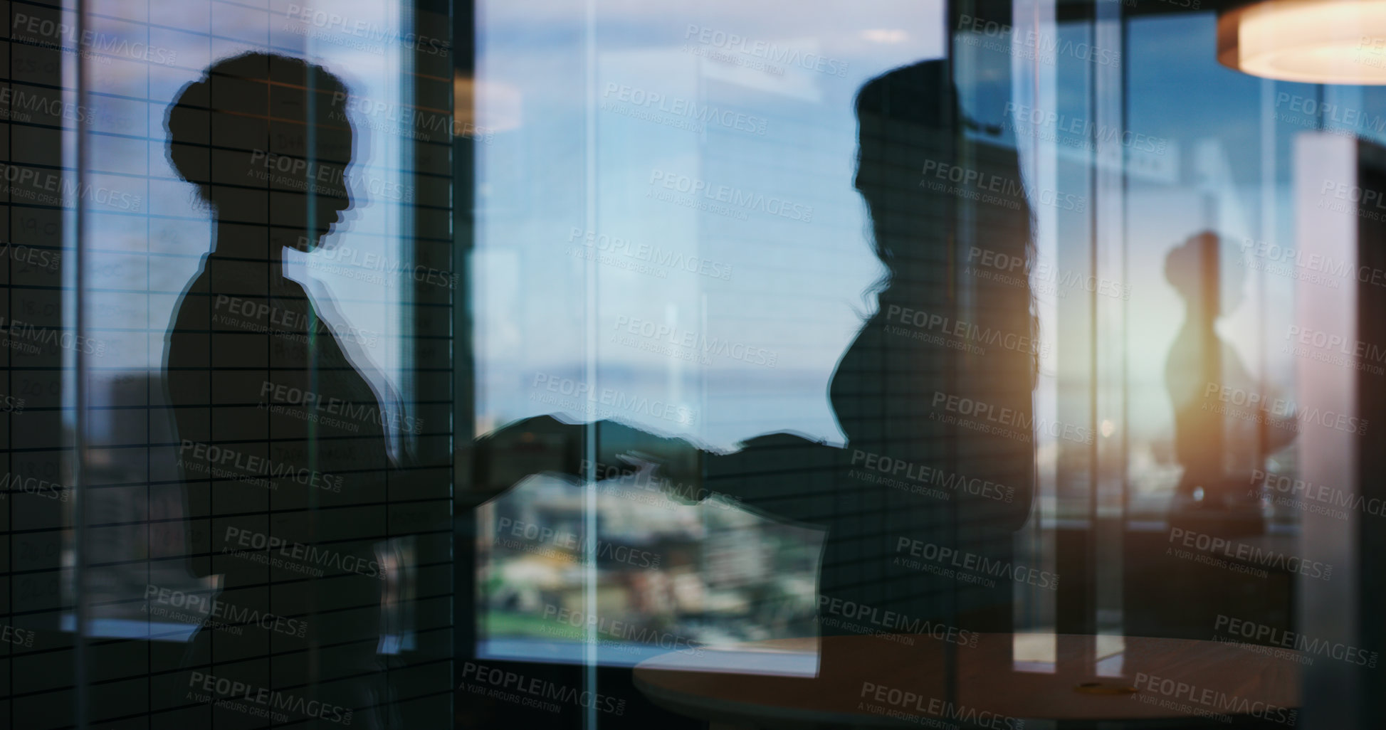 Buy stock photo Silhouette shot of two businesspeople shaking hands inside an office building