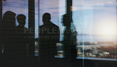 Buy stock photo Silhouette shot of a group of businesspeople having a discussion inside an office building