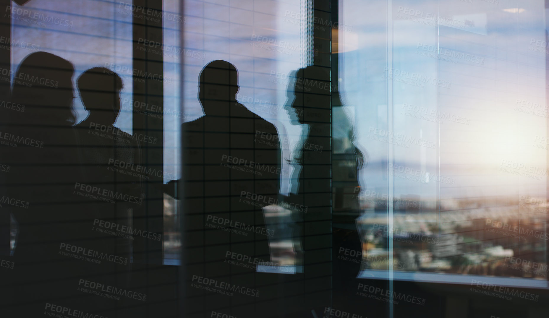 Buy stock photo Silhouette shot of a group of businesspeople having a discussion inside an office building