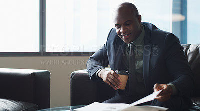 Buy stock photo Cropped shot of a businessman enjoying a cup of coffee while looking at paperwork