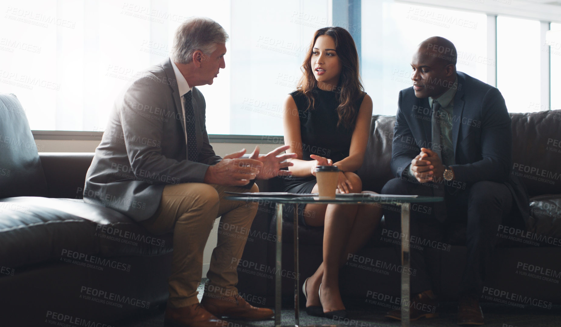 Buy stock photo Shot of a group of businesspeople having a discussion while sitting together on a couch at the office