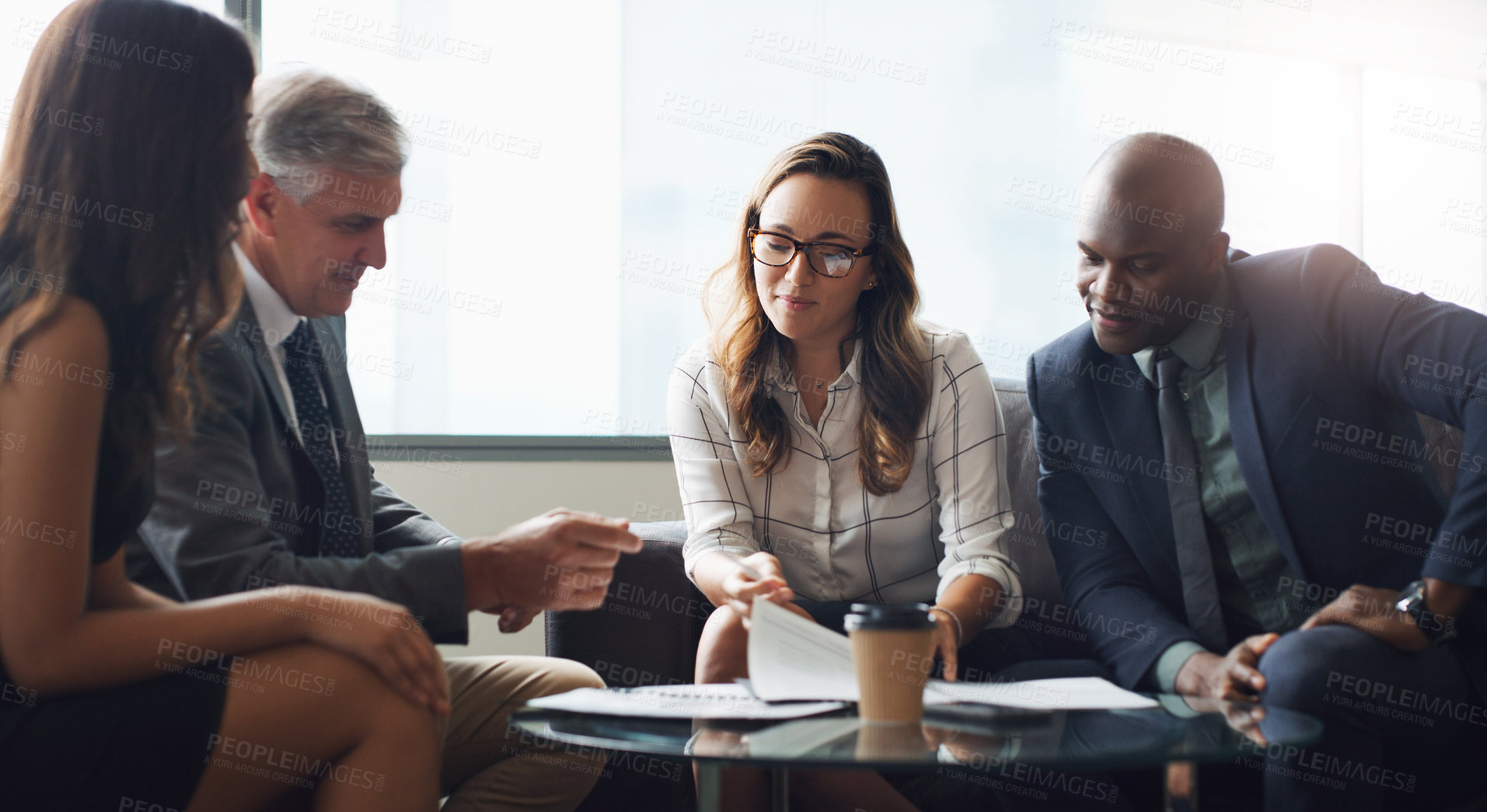 Buy stock photo Shot of a group of businesspeople having a discussion while sitting together on a couch at the office