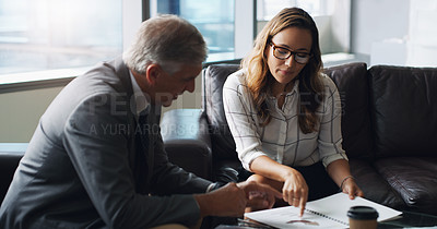 Buy stock photo Shot of two businesspeople having a discussion while sitting on a couch in a modern office