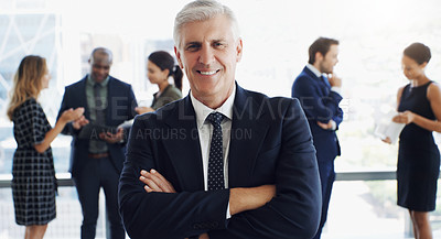 Buy stock photo Shot of a handsome businessman smiling at the camera while colleagues are blurred in the background