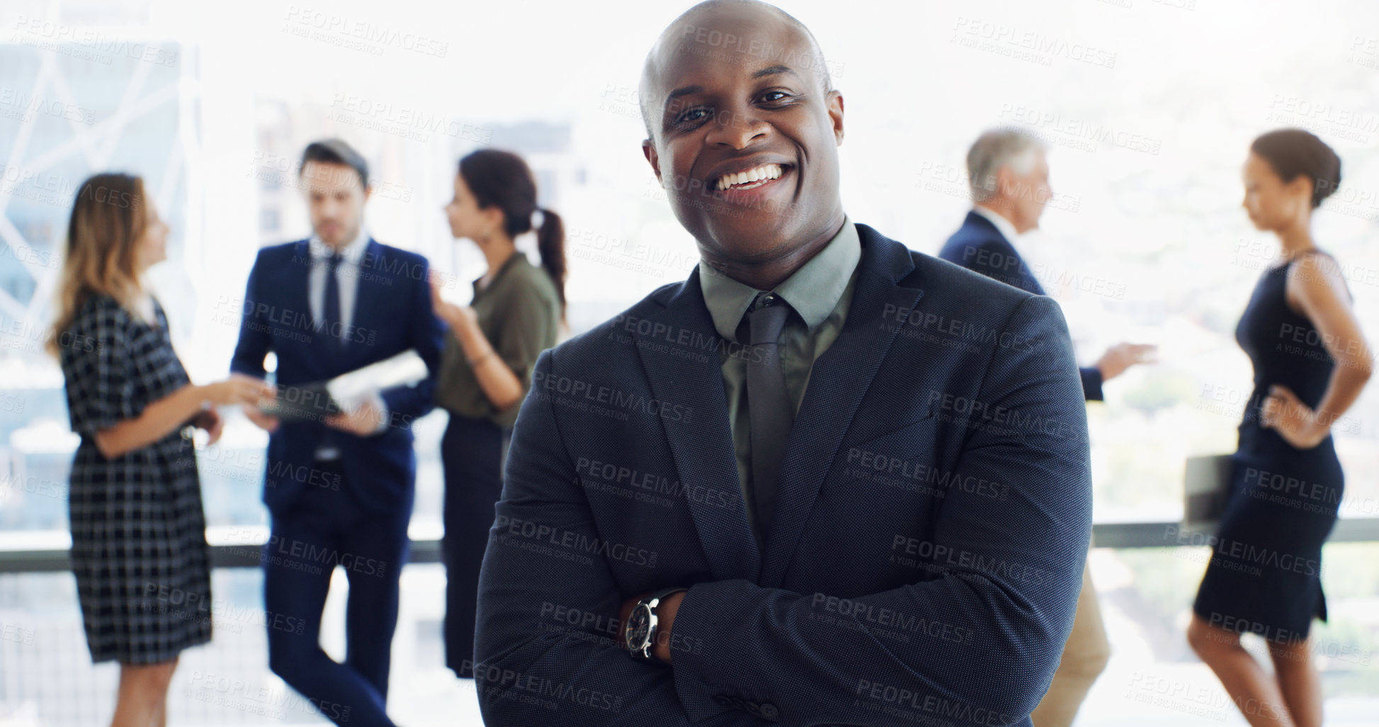 Buy stock photo Shot of a handsome businessman smiling at the camera while colleagues are blurred in the background