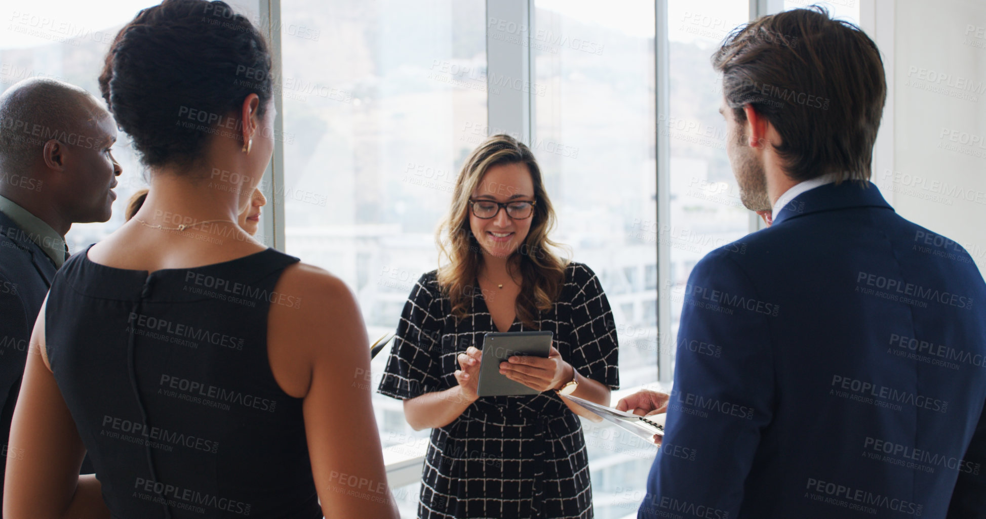 Buy stock photo Shot of a businesswoman using a digital tablet while talking to her colleagues