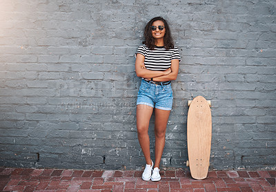 Buy stock photo Portrait of a young woman standing with a skateboard against a grey wall