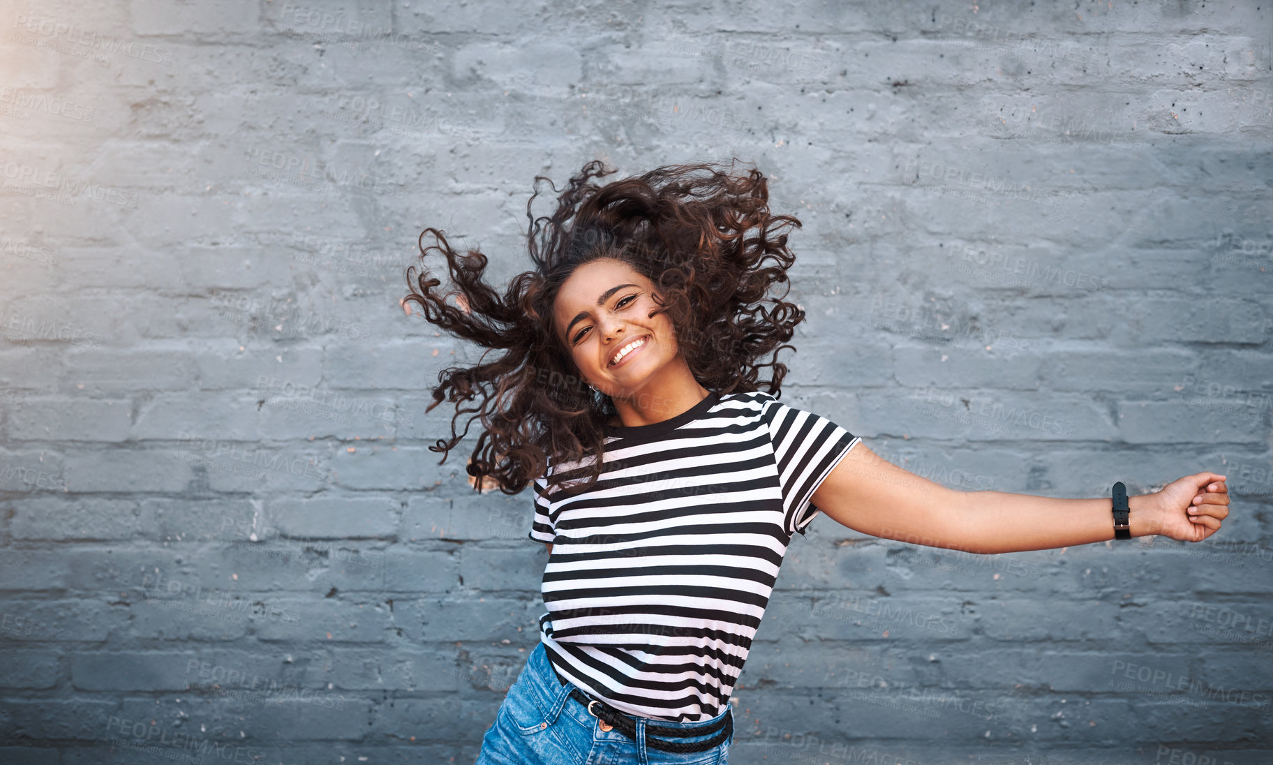 Buy stock photo Portrait of a young woman dancing against a grey wall