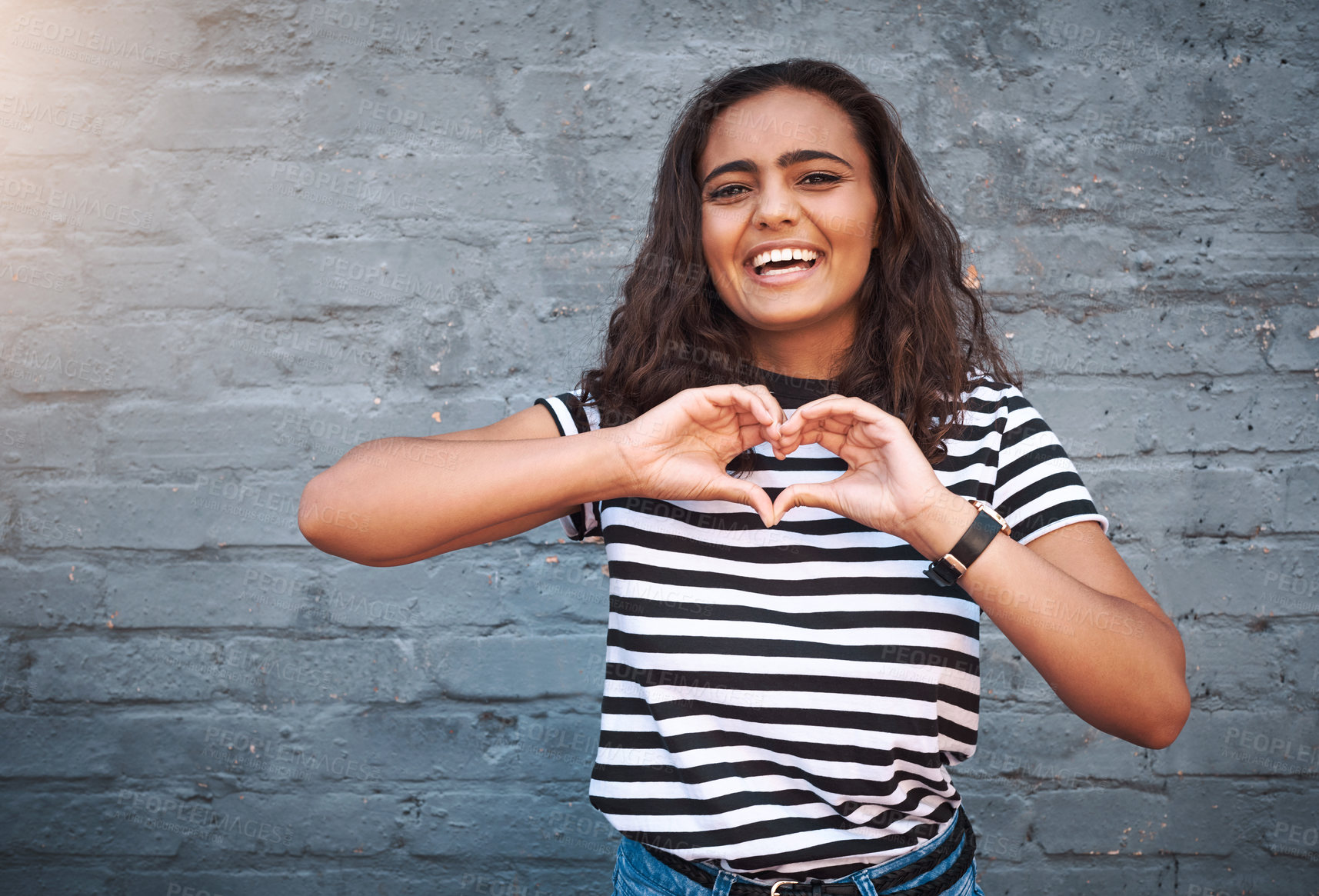 Buy stock photo Brick, wall and heart for girl, smile and hands for gesture, outdoor and break for weekend. Proud, excited and student on holiday, morning and happiness on face, model and city of New York with time