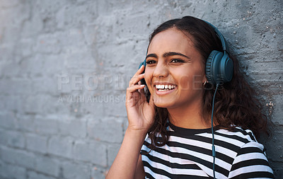 Buy stock photo Girl, headphones and brick wall in city with music playlist or urban traveling, subscription or streaming. Female person, smile and relaxing or funny podcast with humor listening, laughing or sound