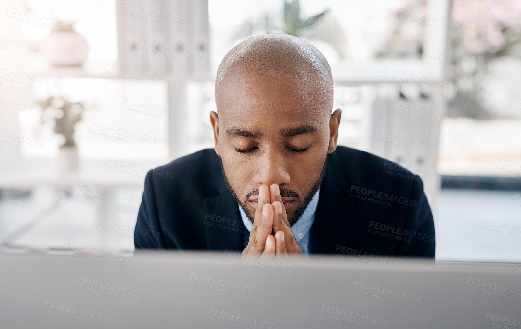 Buy stock photo Cropped shot of a young businessman sitting with his hands clasped at his desk