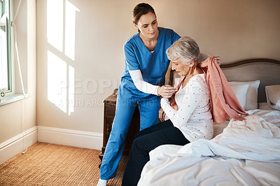 Buy stock photo Shot of a young nurse helping a senior woman get dressed in her bedroom at a nursing home