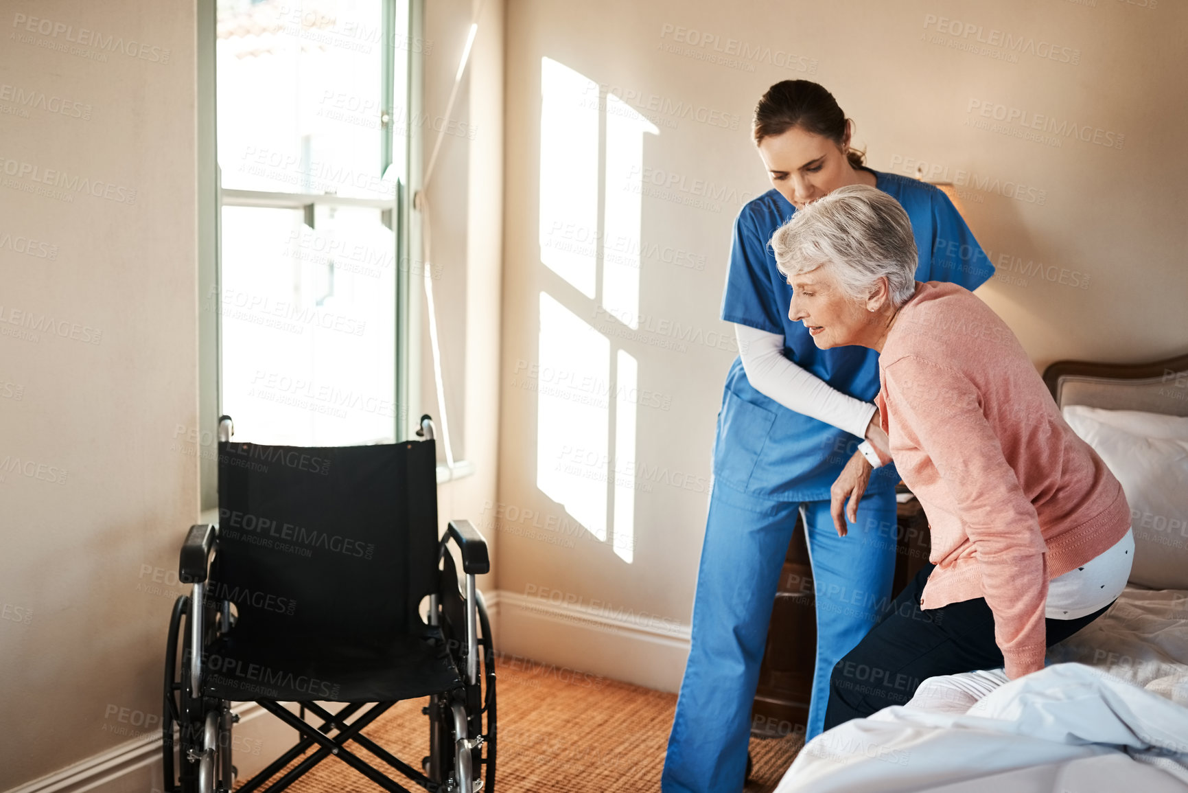 Buy stock photo Shot of a young nurse helping a senior woman get up from her bed in a nursing home