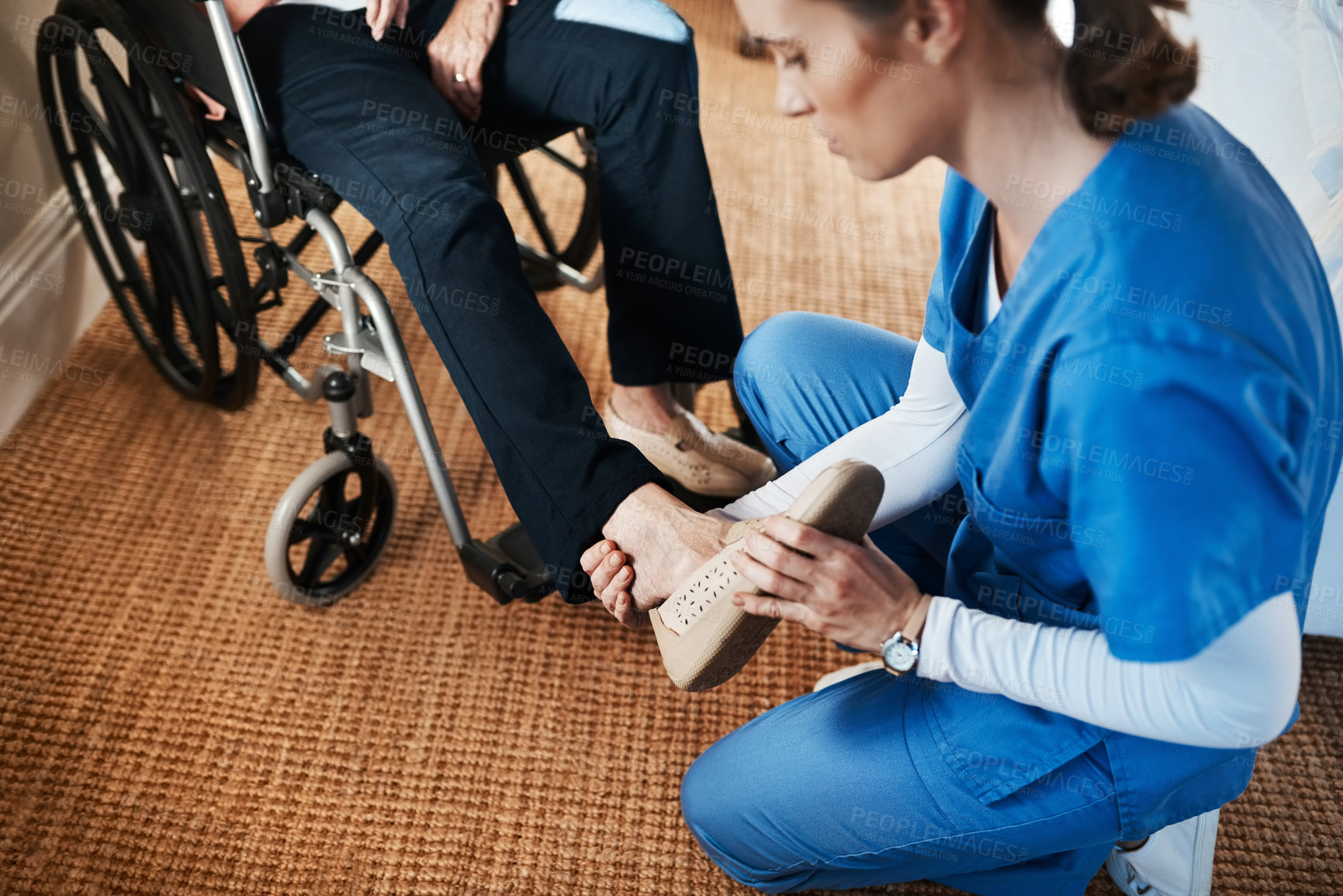Buy stock photo Shot of a young nurse putting on a senior woman’s shoes in a nursing home