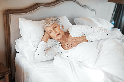 Buy stock photo Shot of a senior woman experiencing chest pain in bed in a nursing home