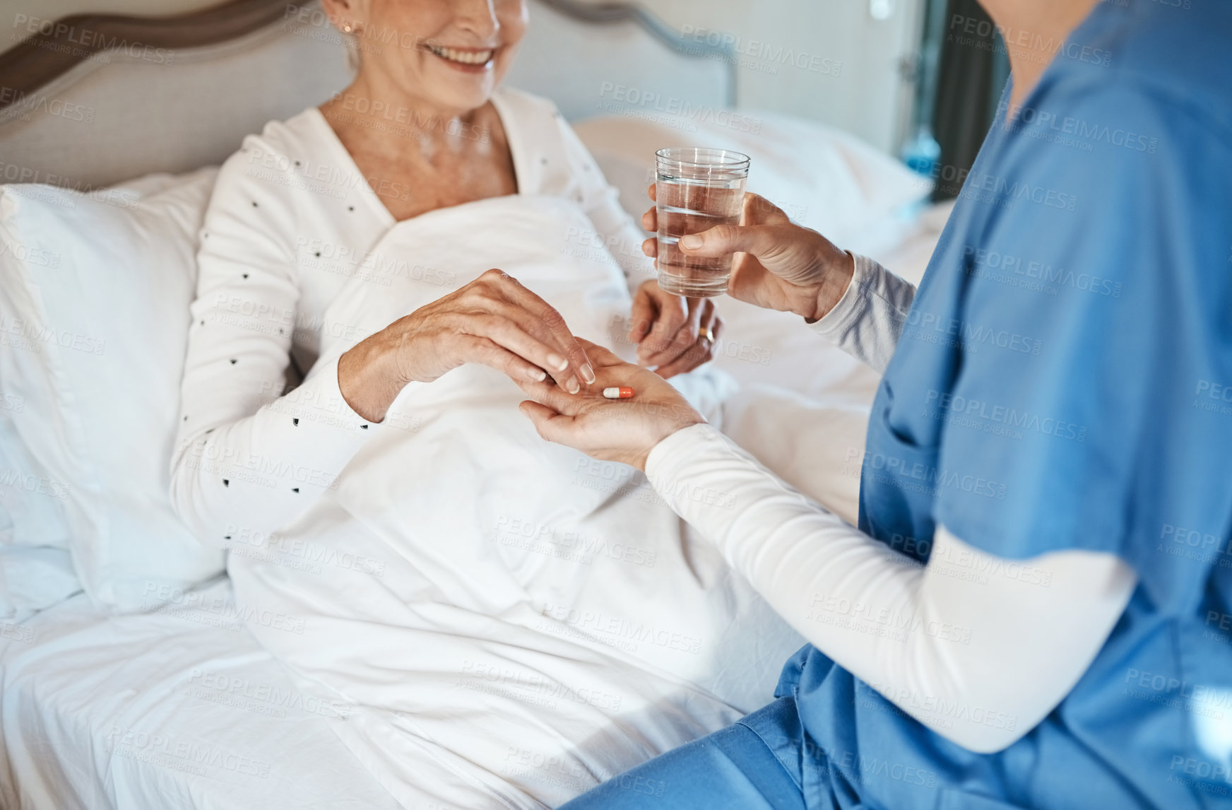 Buy stock photo Shot of a nurse giving a senior woman her medication to take with a glass of water in bed