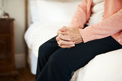 Buy stock photo Cropped shot of a senior woman sitting on the edge of a bed in a nursing home