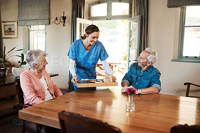Buy stock photo Shot of a young nurse checking up on a senior couple during breakfast at a nursing home