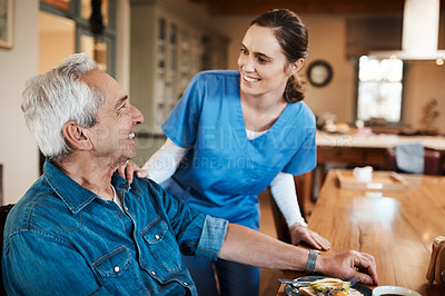 Buy stock photo Shot of a young nurse checking up on a senior man during breakfast at a nursing home