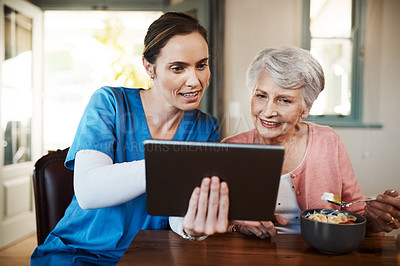 Buy stock photo Shot of a young nurse and senior woman using a digital tablet at breakfast time in a nursing home