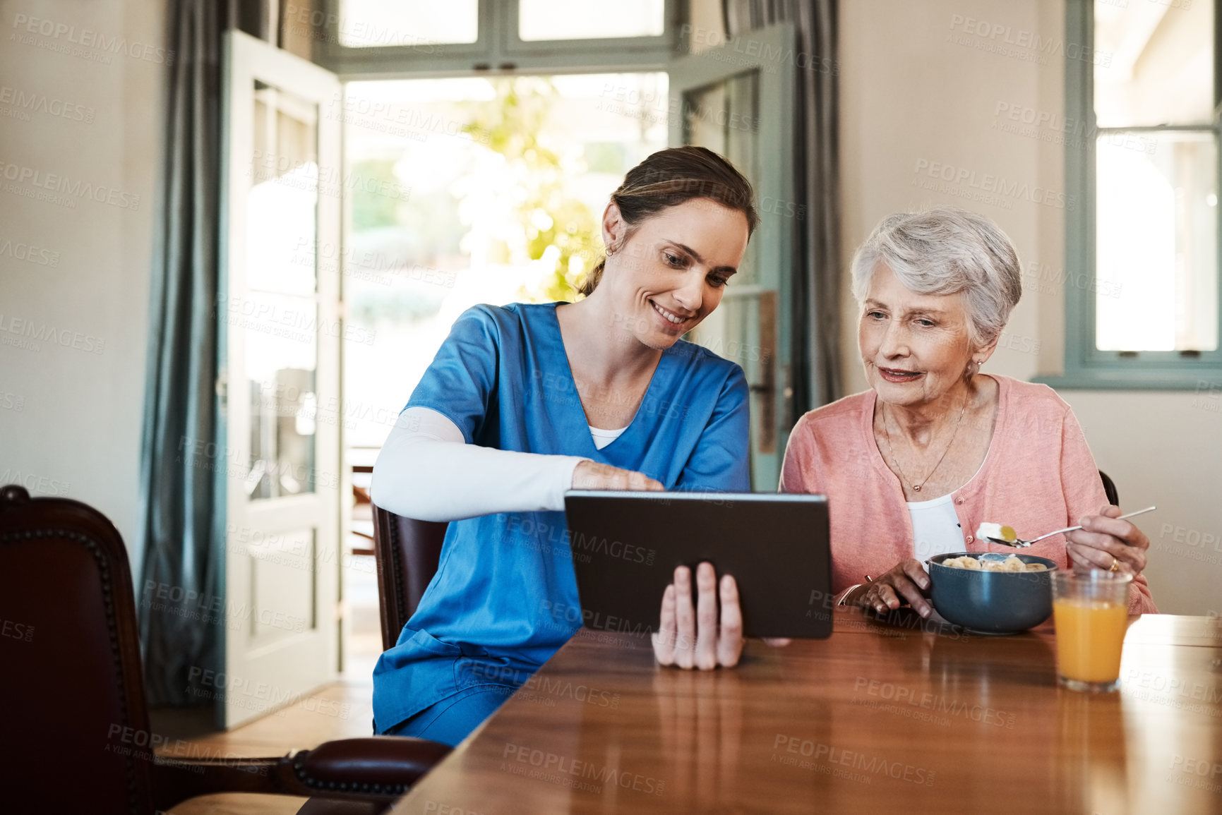 Buy stock photo Shot of a young nurse and senior woman using a digital tablet at breakfast time in a nursing home