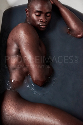 Buy stock photo Shot of a handsome young man submerged in a bath filled with dark water