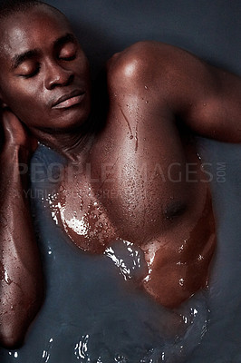 Buy stock photo Shot of a handsome young man submerged in a bath filled with dark water