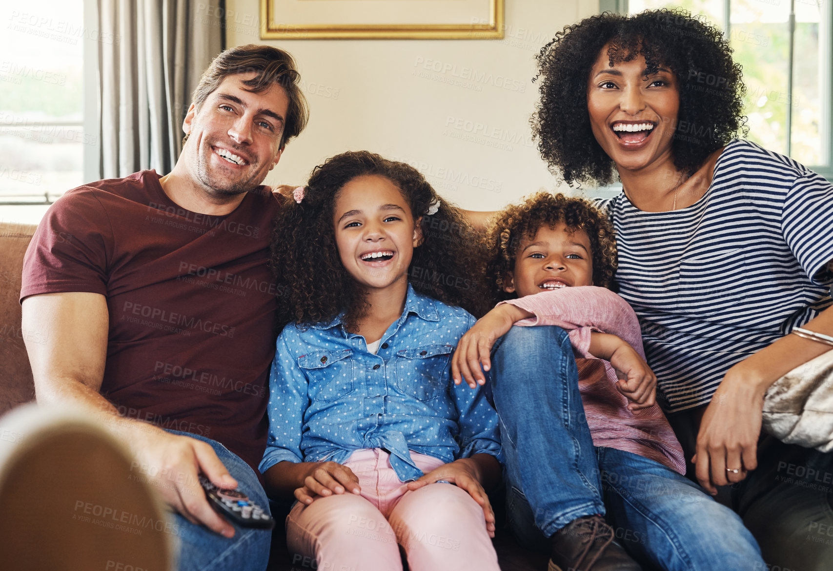 Buy stock photo Shot of a beautiful young family of four watching tv together at home