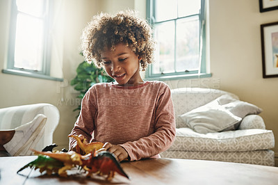 Buy stock photo Shot of an adorable little boy playing with his toy dinosaurs at home