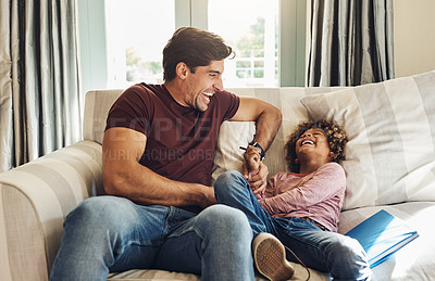 Buy stock photo Shot of a happy young father and son playing together on a sofa at home