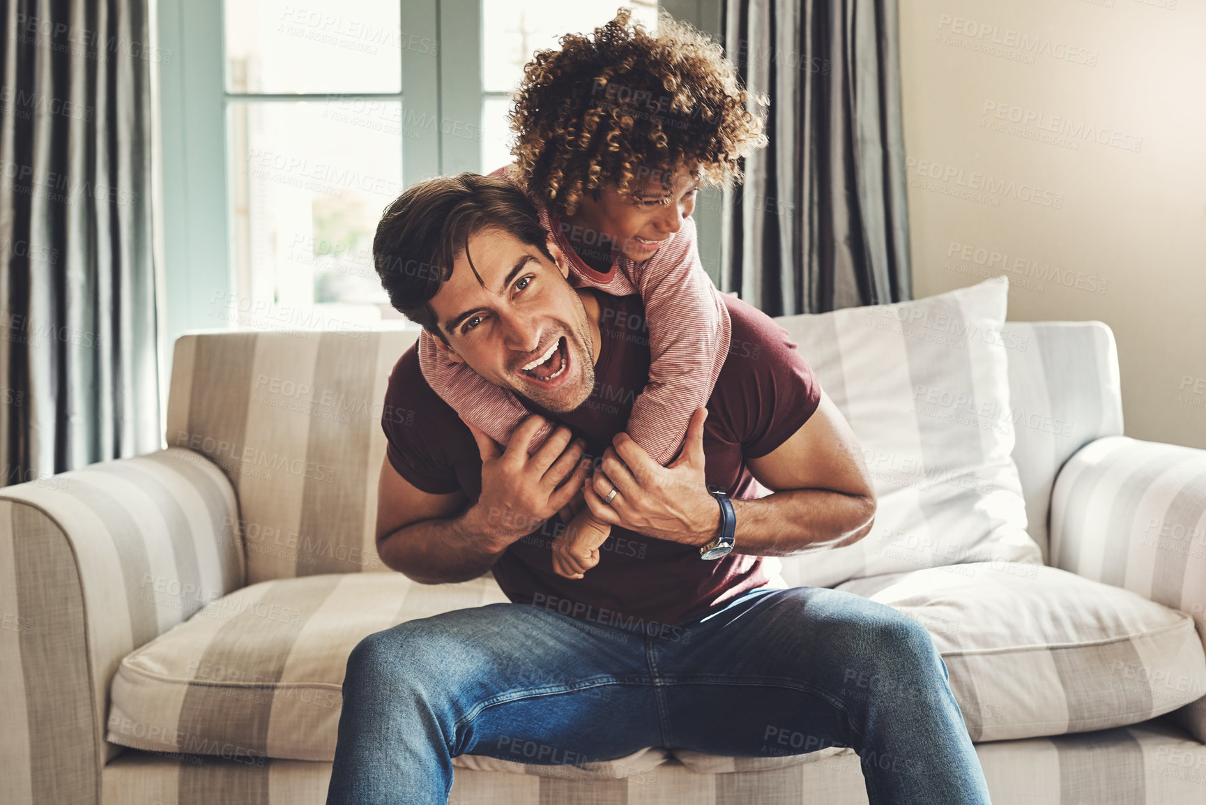Buy stock photo Portrait of a happy young father and son playing together on a couch at home
