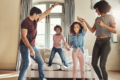 Buy stock photo Full length shot of a happy young family of four dancing together at home