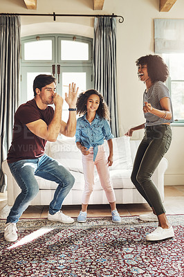 Buy stock photo Full length shot of a happy young family of three dancing together at home
