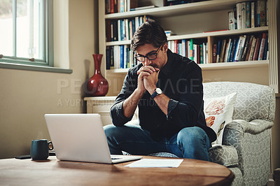 Buy stock photo Shot of a young businessman looking stressed out while working on a laptop in his office at home