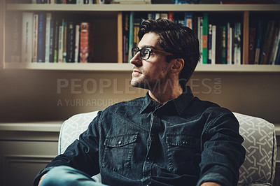 Buy stock photo Shot of a handsome young businessman looking thoughtful while sitting on a couch in his office at home