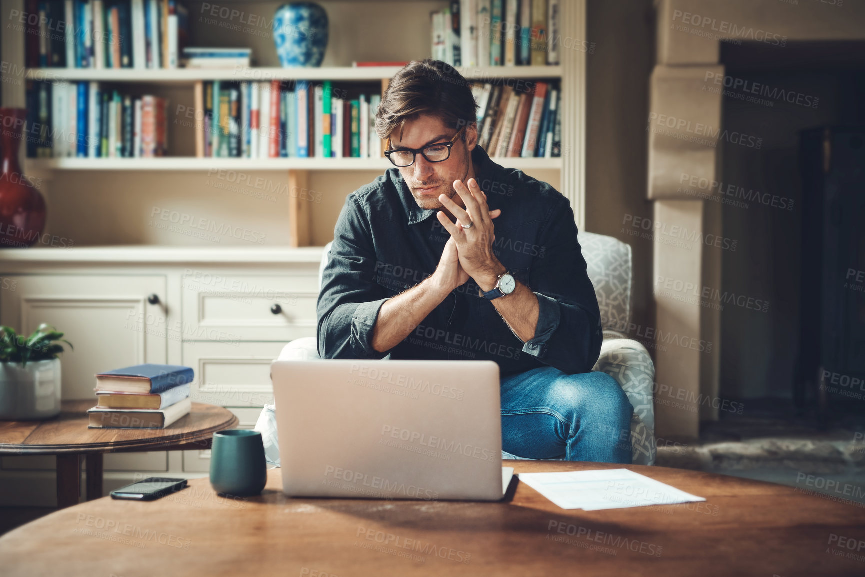 Buy stock photo Shot of a handsome young businessman working on a laptop in his office at home