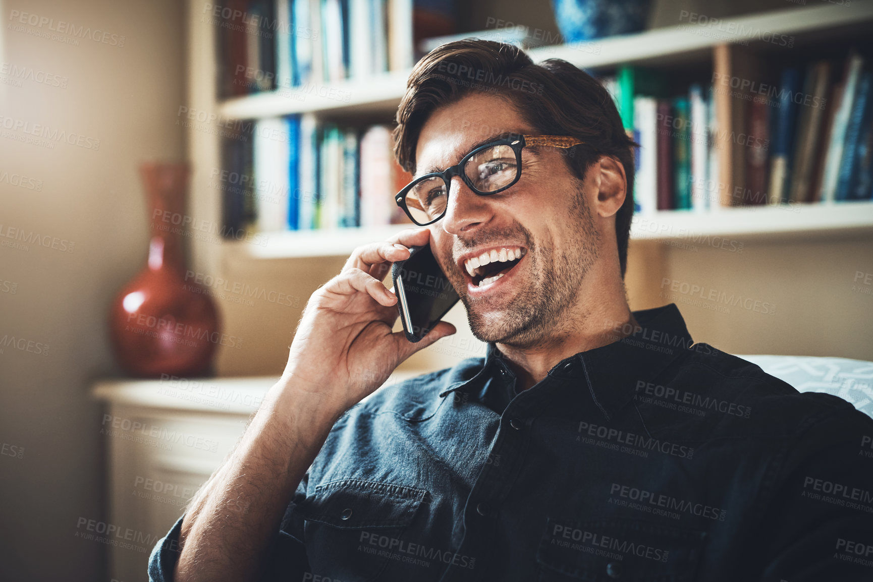 Buy stock photo Shot of a handsome young businessman making a phone call in his office at home