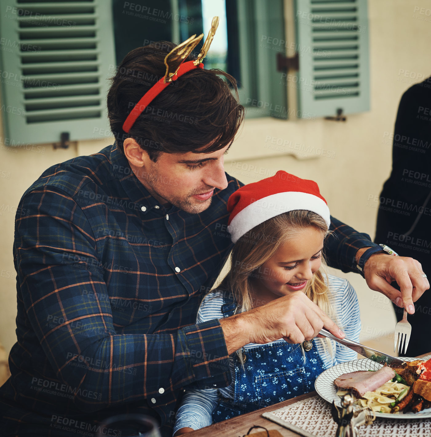 Buy stock photo Shot of an adorable little girl celebrating Christmas over lunch with her father at home