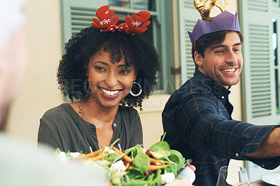Buy stock photo Shot of a beautiful young couple dishing up food together at a Christmas lunch party