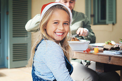 Buy stock photo Portrait of an adorable little girl feeling cheerful while celebrating Christmas over lunch with her family