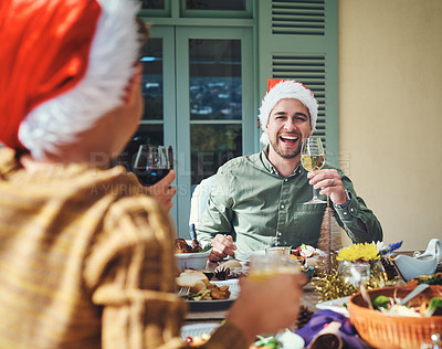 Buy stock photo Portrait of a handsome young man enjoying himself at a Christmas lunch party with friends and family
