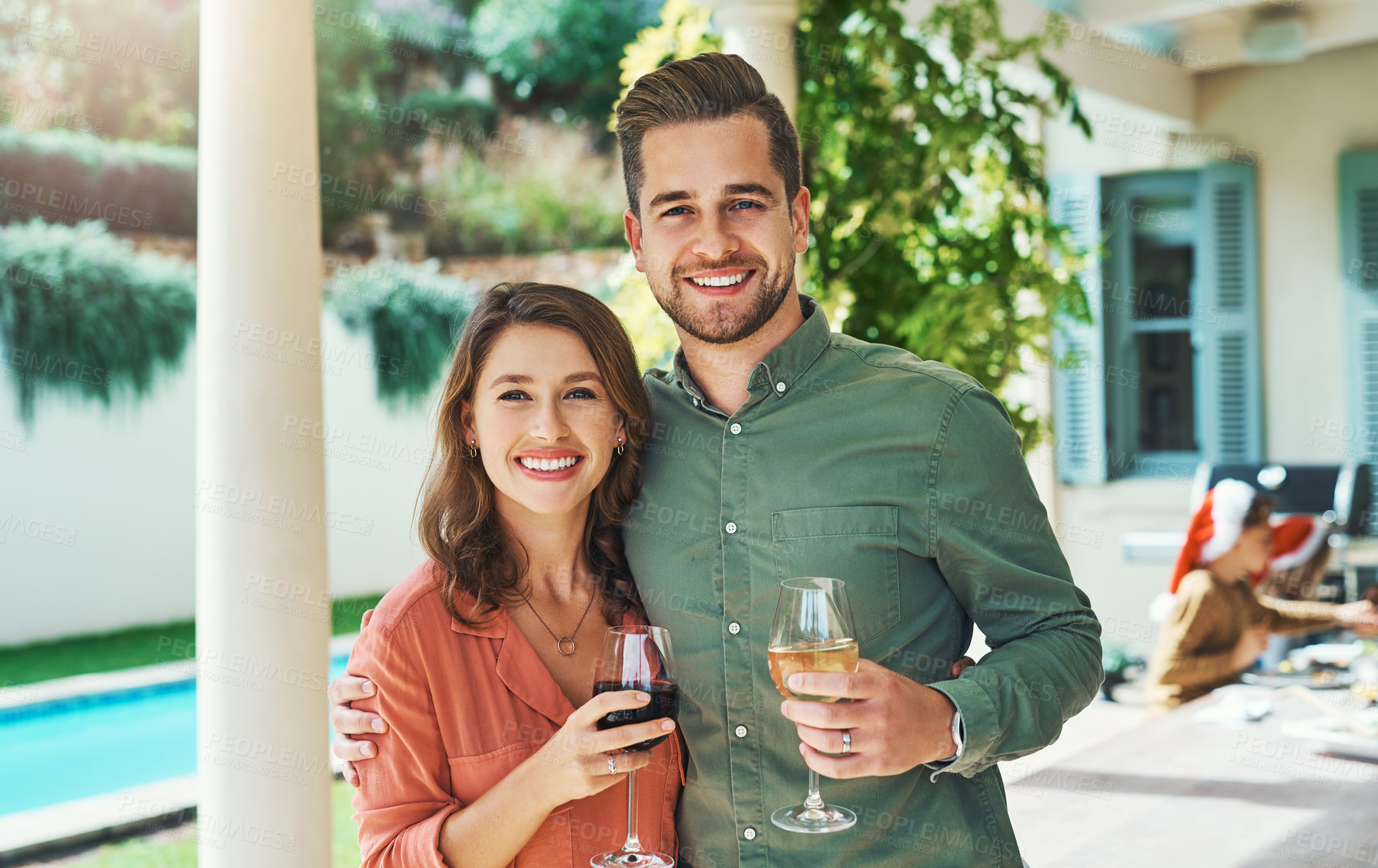 Buy stock photo Portrait of a happy young couple celebrating Christmas together over lunch with friends and family in the background