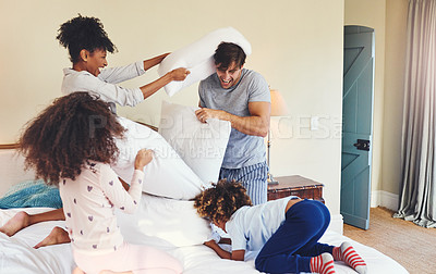 Buy stock photo Shot of a family having a pillow fight in the bedroom together at home