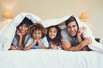 Buy stock photo Portrait of a happy family relaxing together underneath a blanket at home