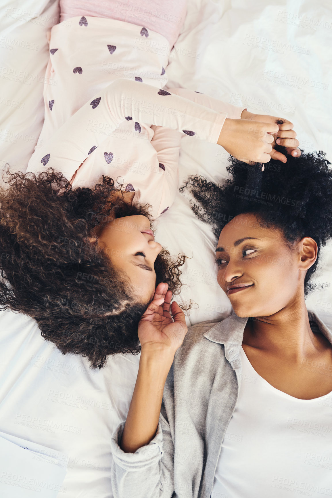 Buy stock photo High angle shot of a mother and her little daughter lying down on a bed together at home