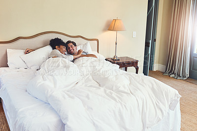 Buy stock photo Shot of a young couple relaxing in bed together at home