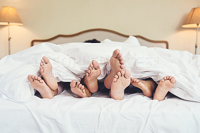 Buy stock photo Shot of a family's feet peeking out from a blanket at home