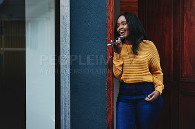 Buy stock photo Shot of a beautiful young businesswoman using her cellphone while standing on a doorway outside of a building