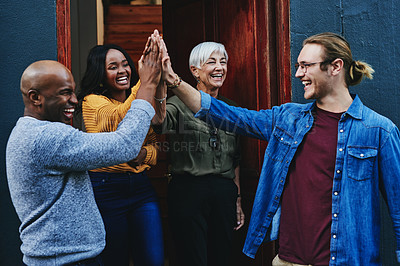 Buy stock photo Shot of a group of businesspeople joining together for a high five while standing outside their office building